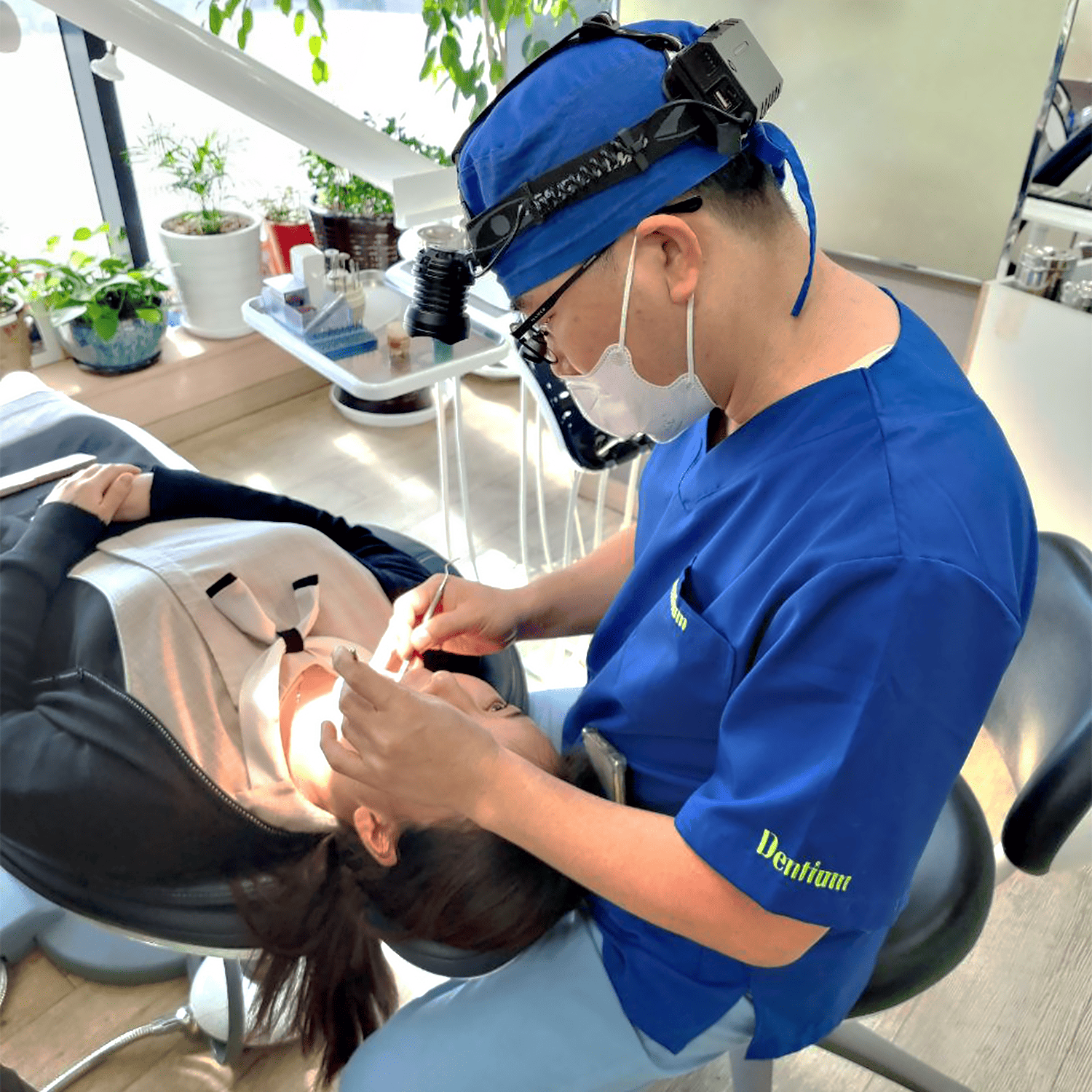 Dentist in blue scrubs performing dental work on a patient in a modern clinic.