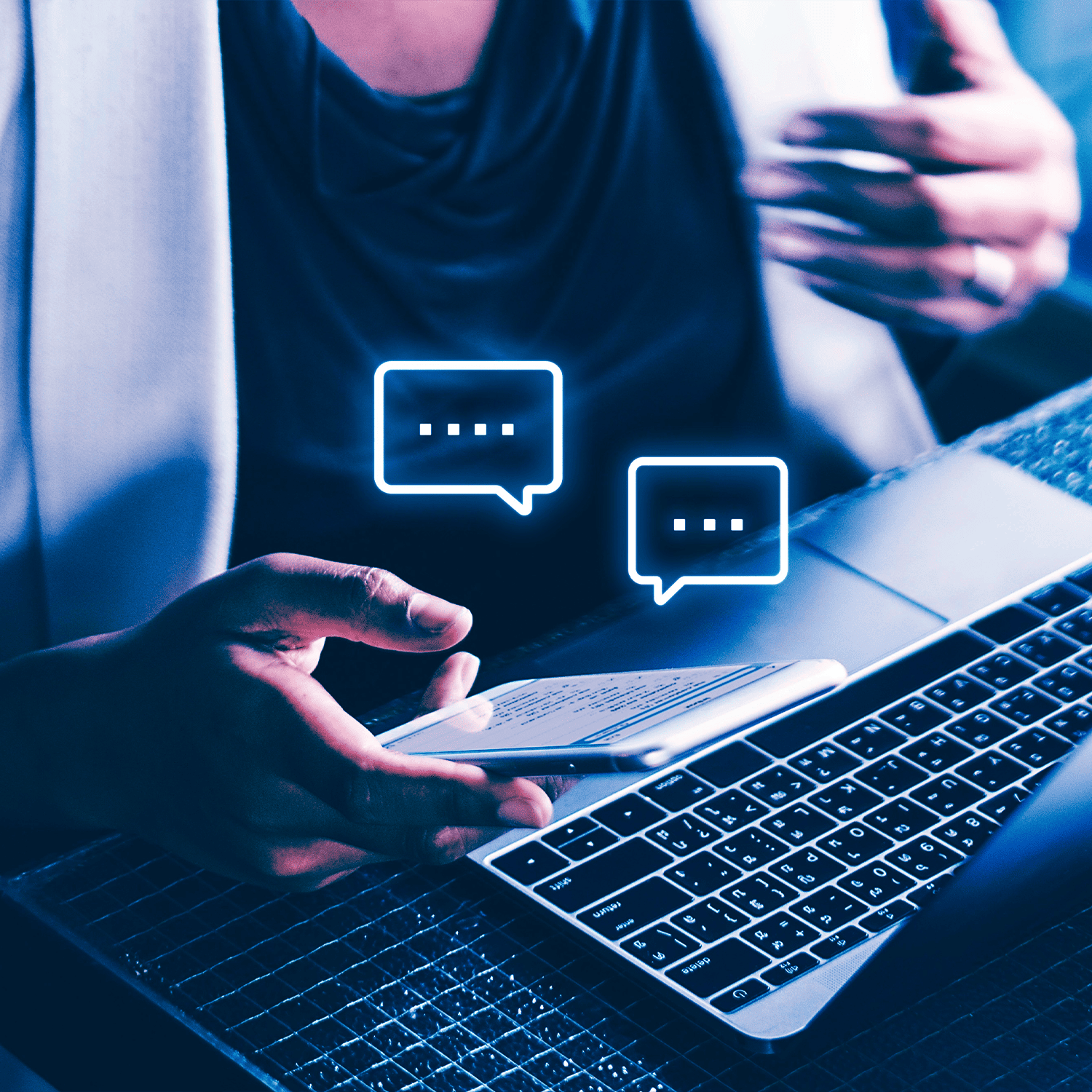 Person using a laptop with smartphone, surrounded by chat bubble icons.