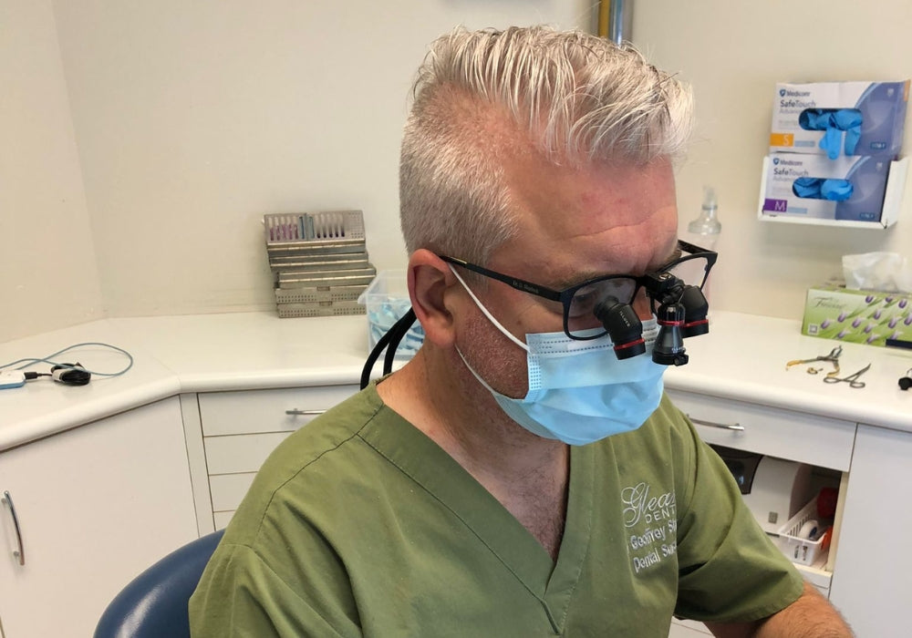 Dentist wearing illuco loupes in green scrubs