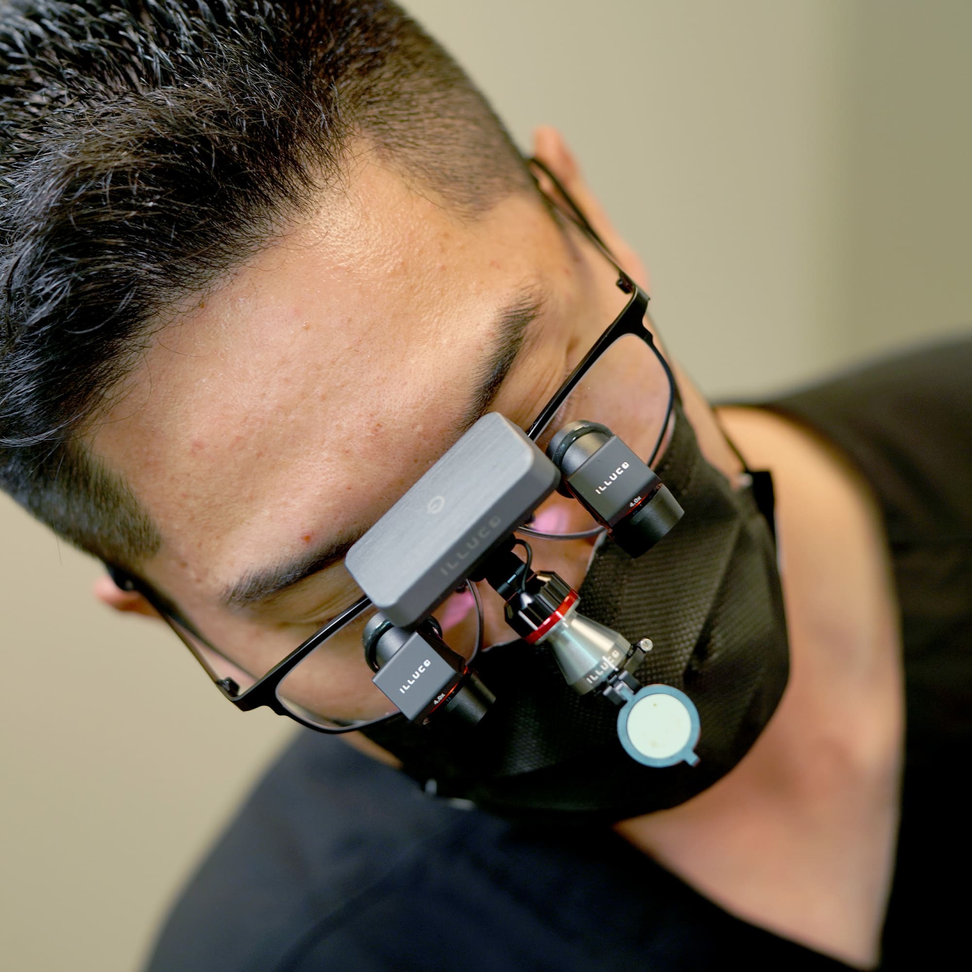 doctor wearing a black face mask with ILLUCO Ergo X Angled Loupes and Wireless Headlight