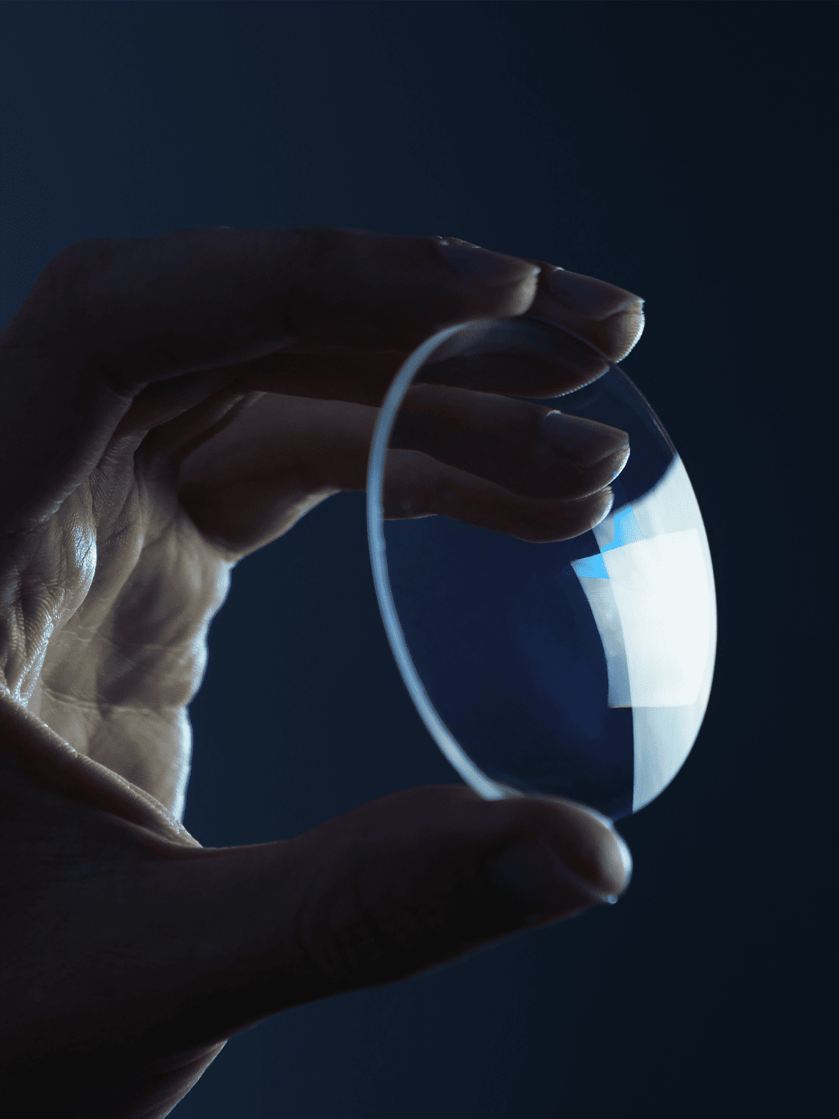 Hand holding a lens against a dark background